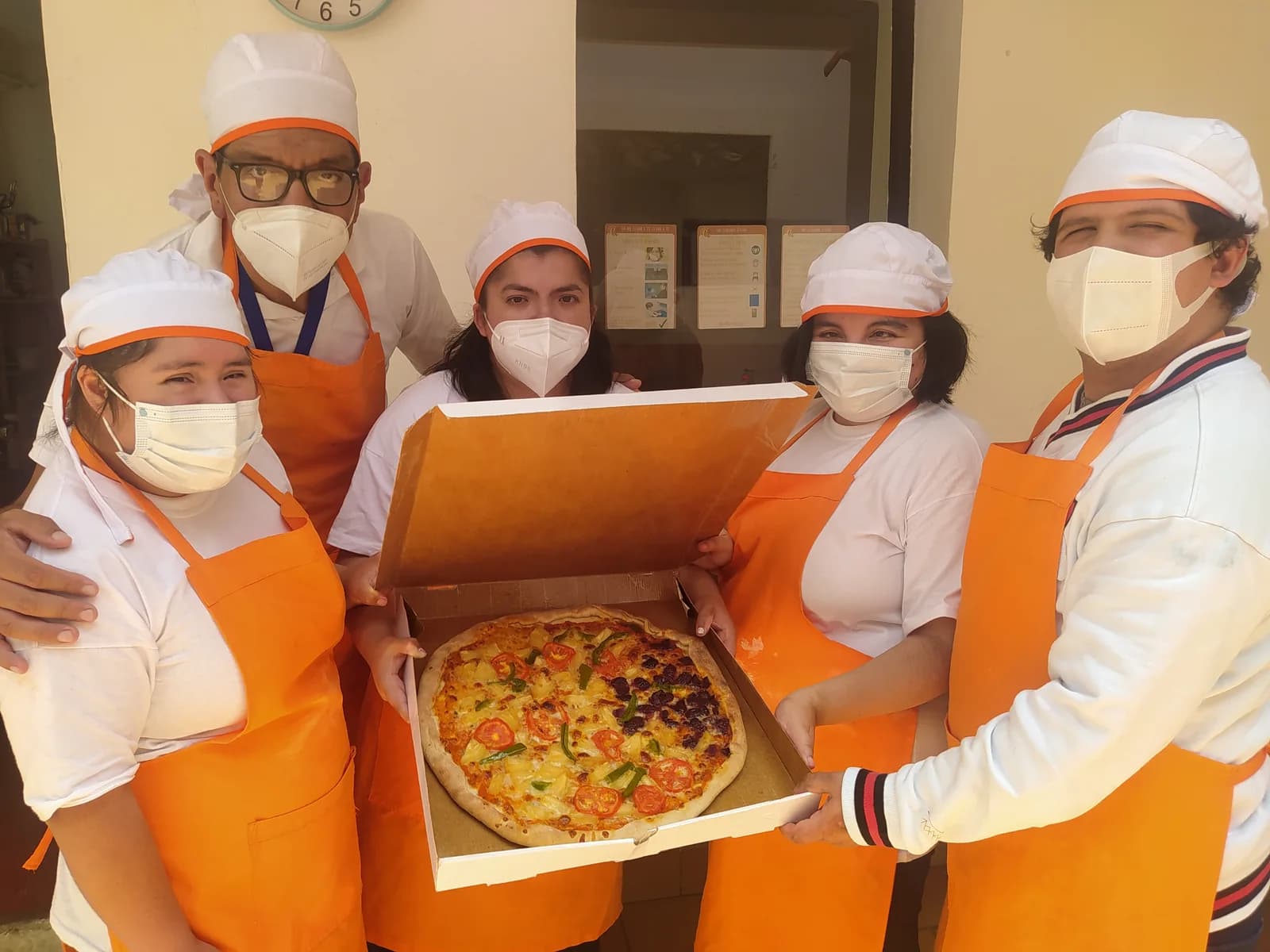 Equipo del taller de pizzería de Sol en Casa con una pizza lista para entregar